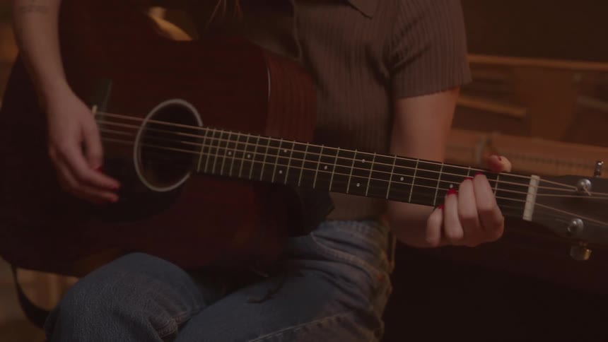 The woman is strumming her guitar