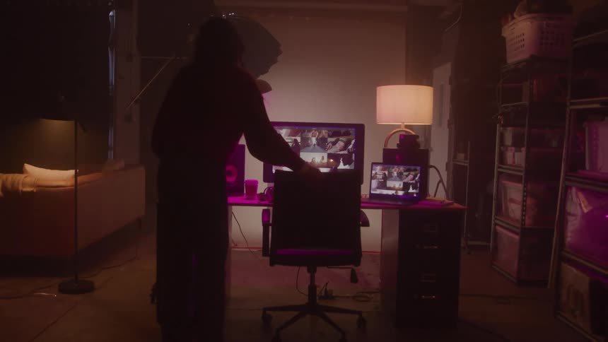 Woman sets up the scene of a photography studio and then puts on her headphones and sits in front of a computer