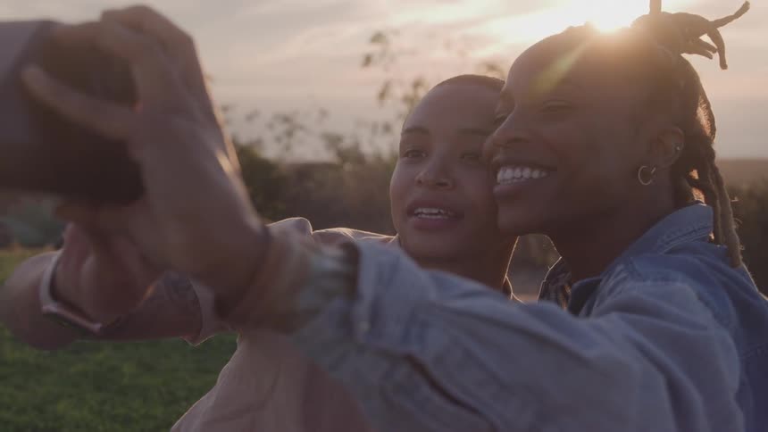 Two smiling women taking a photo in the late afternoon