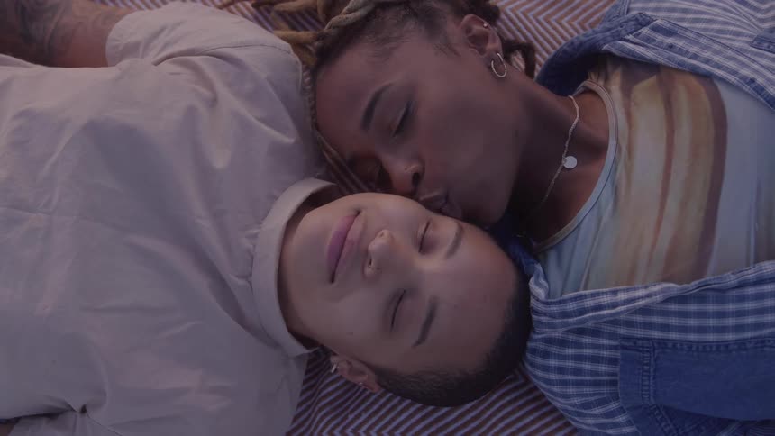 Woman kissing another while they are lying down