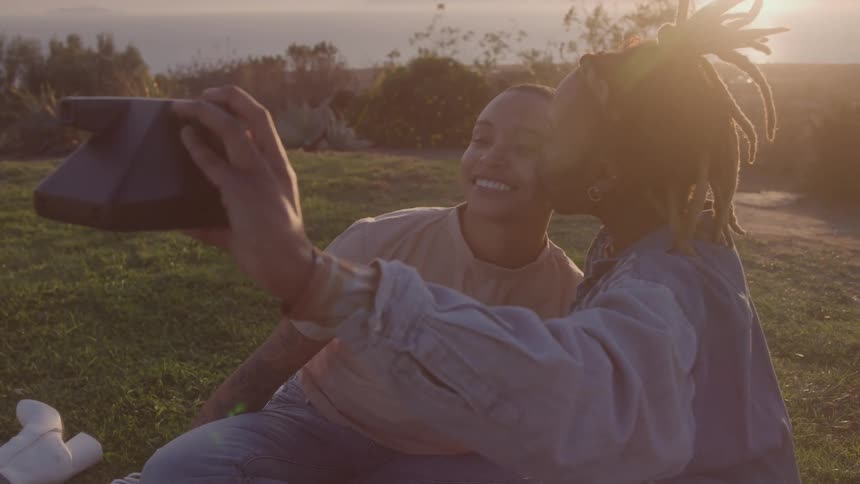 Couple of women taking a photo in the late afternoon in an outdoor environment smiling