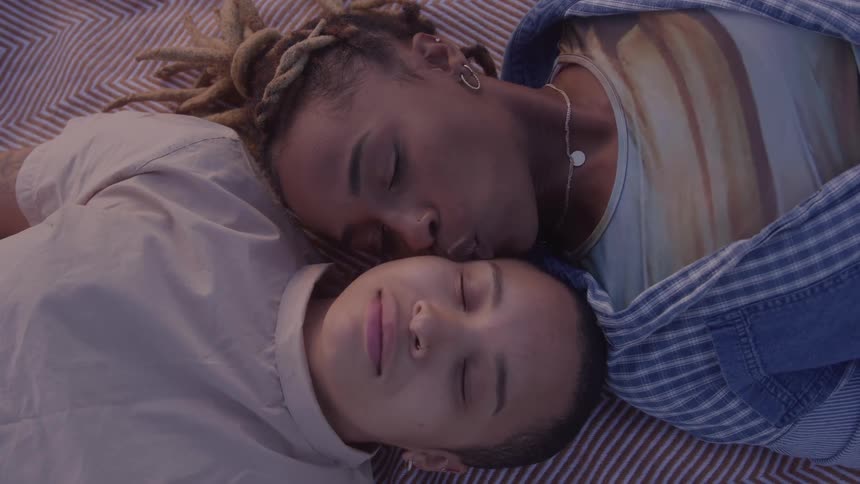 Woman kissing her partner on the cheek while they are lying down