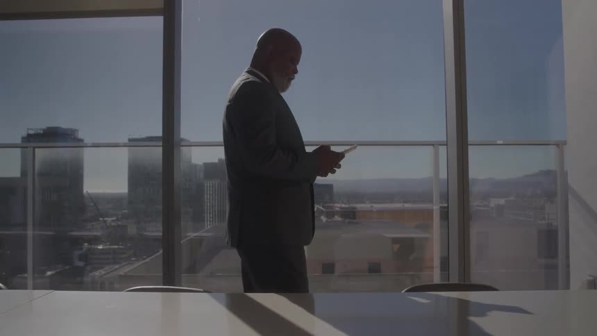 The man is texting in the conference room