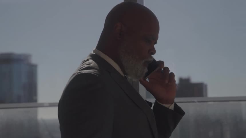 Man in suit walking and talking on cell phone indoors