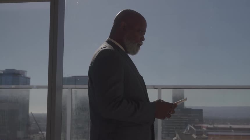 A man stands and looks at a phone in an office