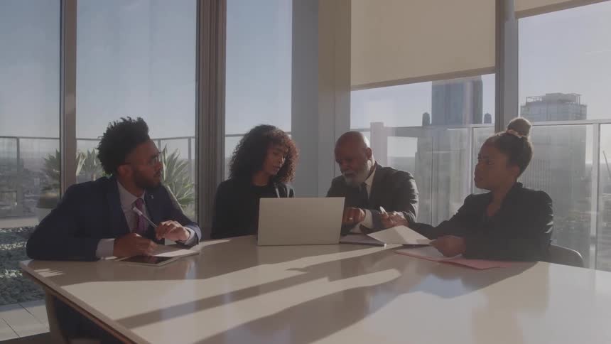 Four people sitting and talking in an office meeting