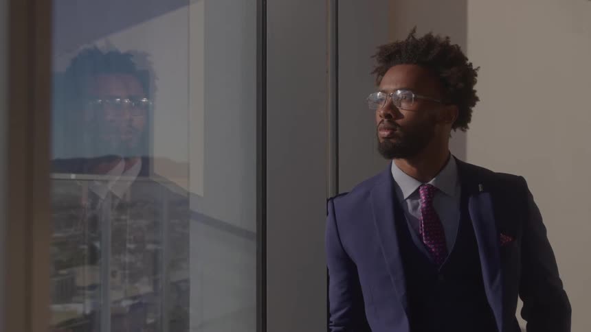 The man leans against the office window viewing the city