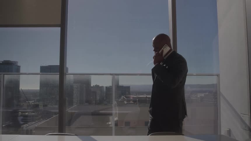 The man is talking on his cell phone in the conference room