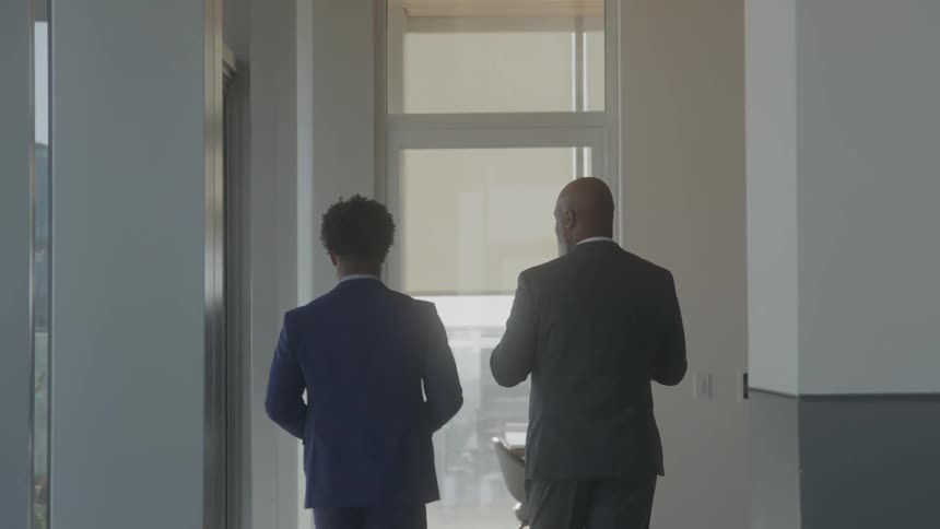 Two men have a discussion in the hallway