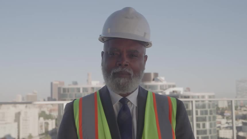 The man is wearing a hard hat on the balcony