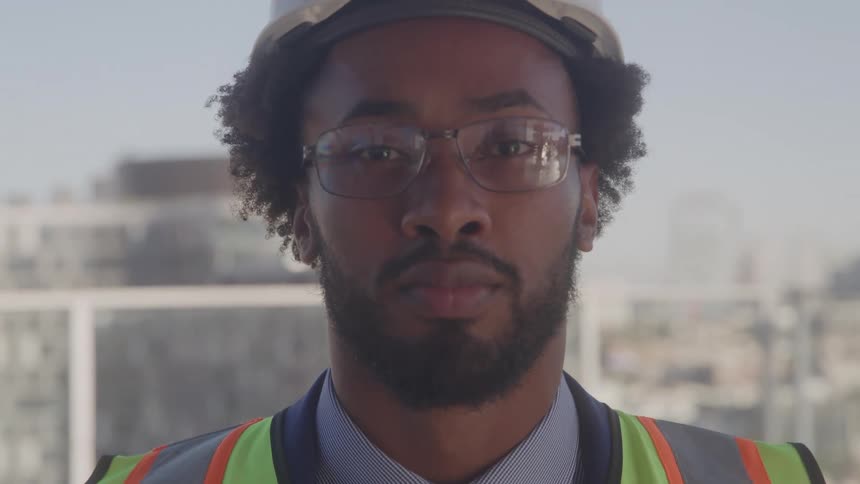 The man is wearing a hard hat high up on the balcony