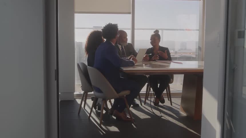 A group of black executives discussing at a table in a conference room during daytime