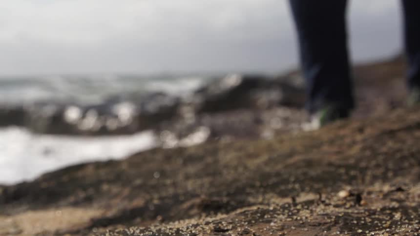 Person walks along the water on rocks