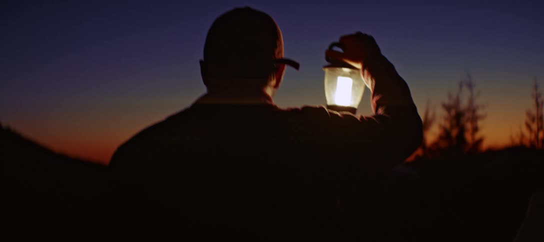 The man walks at night lighting the way with a lantern
