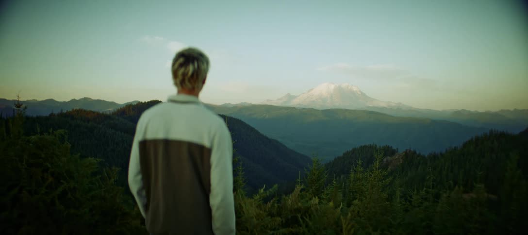 A young man is walking to contemplate the view of a mountain landscape