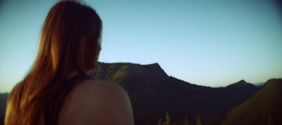 A woman looks out at the mountains under a clear sky