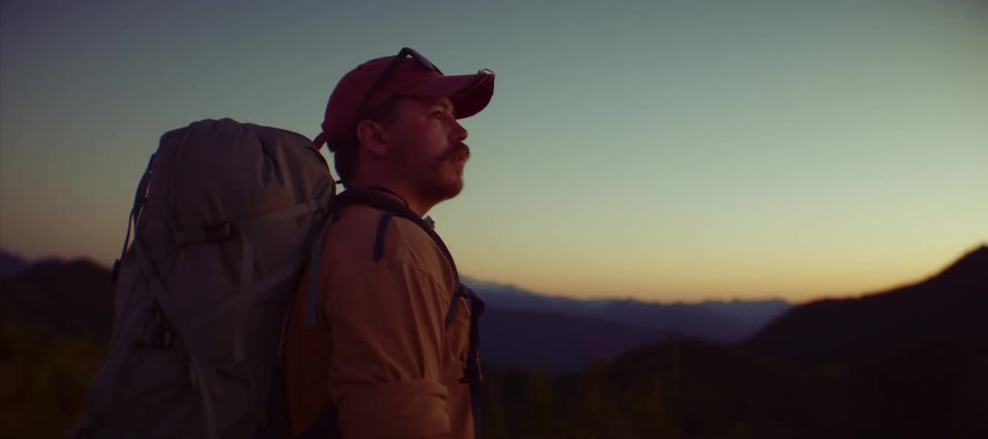 The man looks out over to the horizon full of mountains