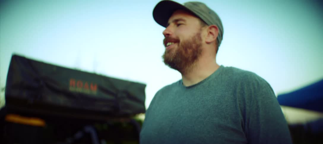 Young man with a beard wearing a hat cooking on a grill outdoors