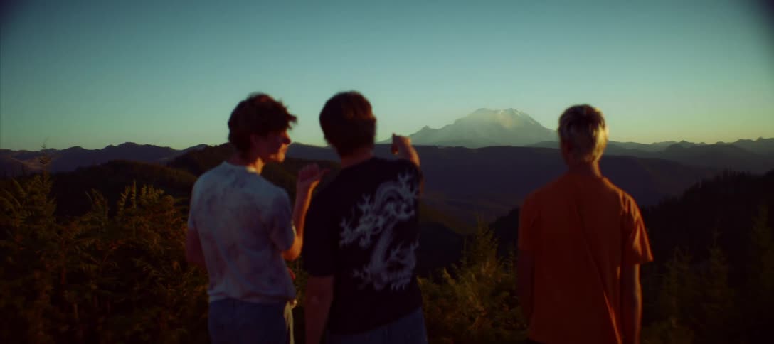 Three young men enjoy the mountainous landscape in the late afternoon