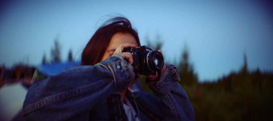 Close up of a young female photographer taking photos with a camera outdoors during daytime
