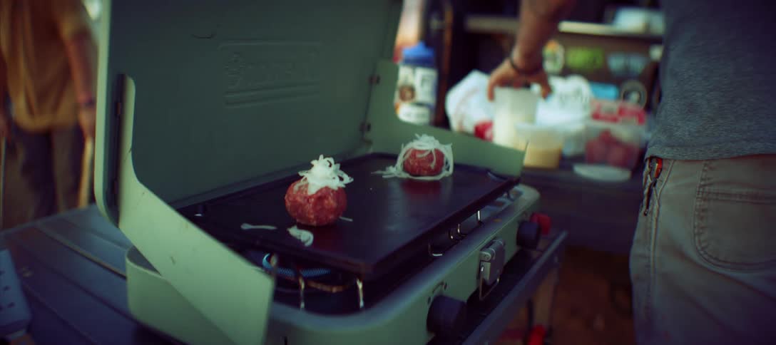 The man grills burgers at the campsite