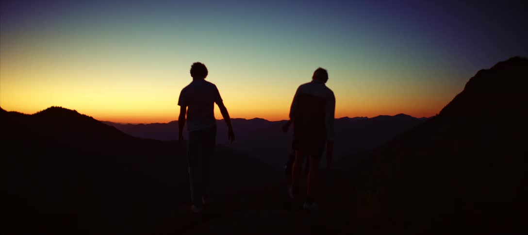 Silhouette of three people walking through the mountains in the late afternoon