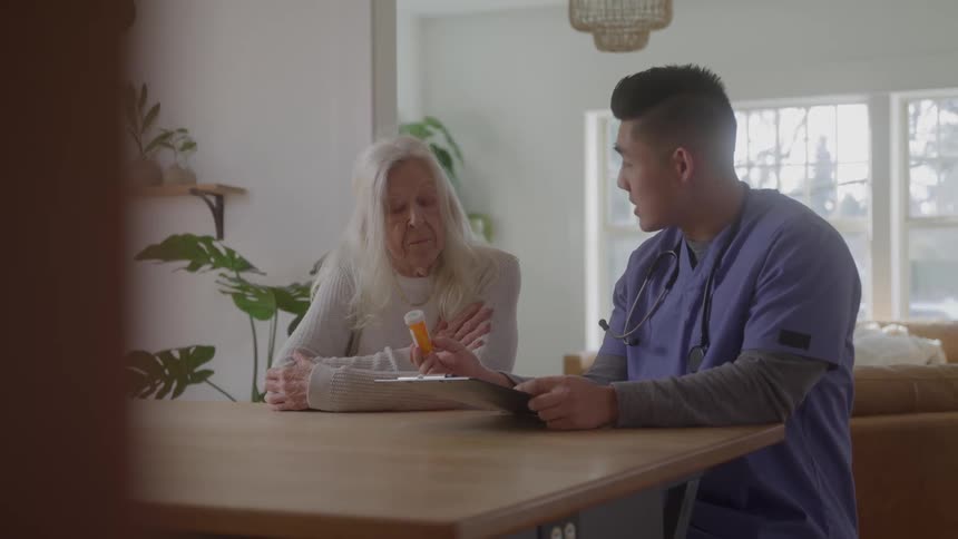 Nurse sitting at desk talking to elderly patient