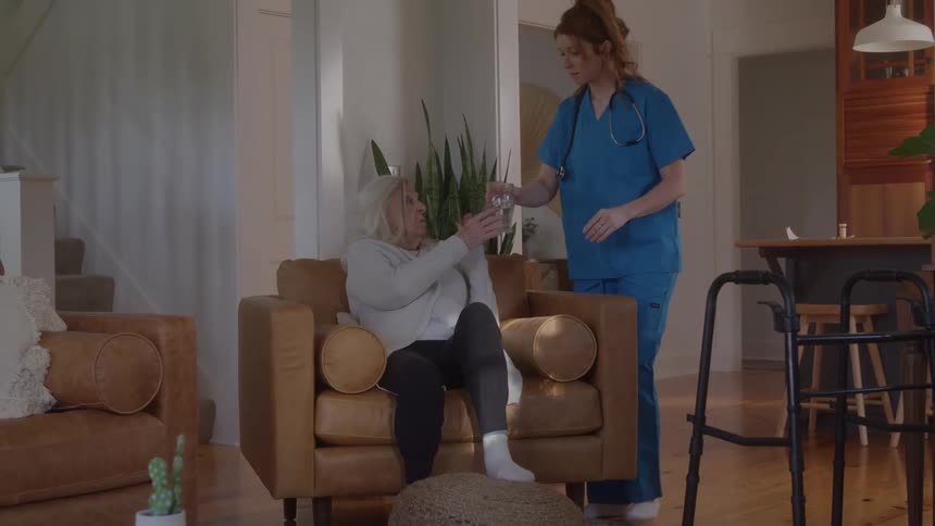 The home health aid brings a glass of water to a patient