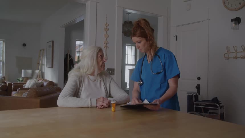 Nurse talking to an elderly patient showing her a medicine