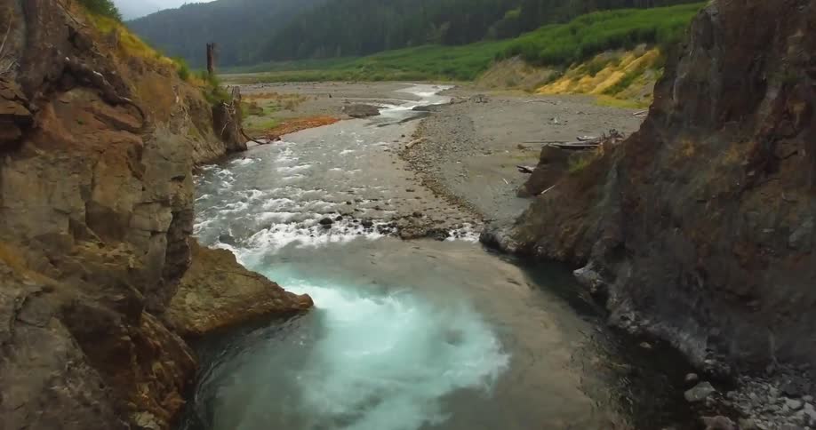 The valley is covered with green with a stream going through the middle