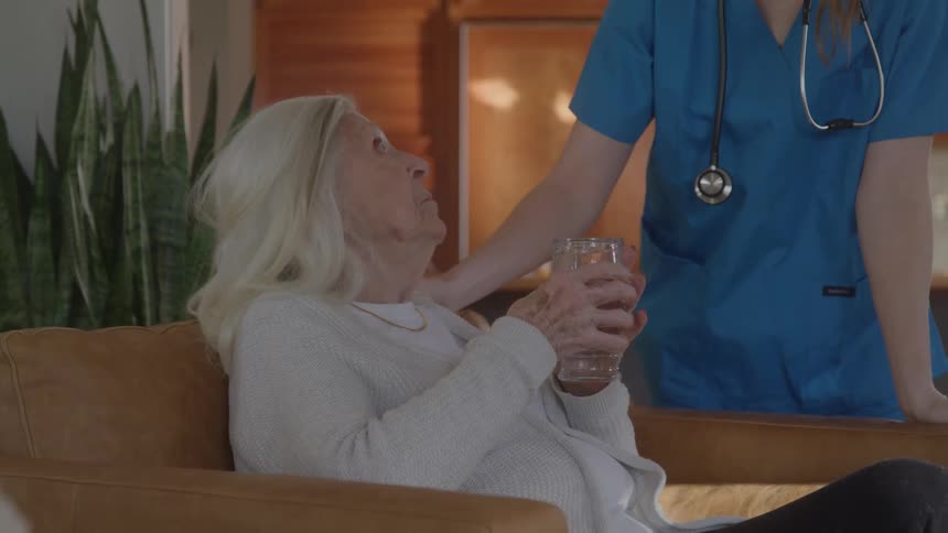 Nurse handing a glass of water to an elderly woman