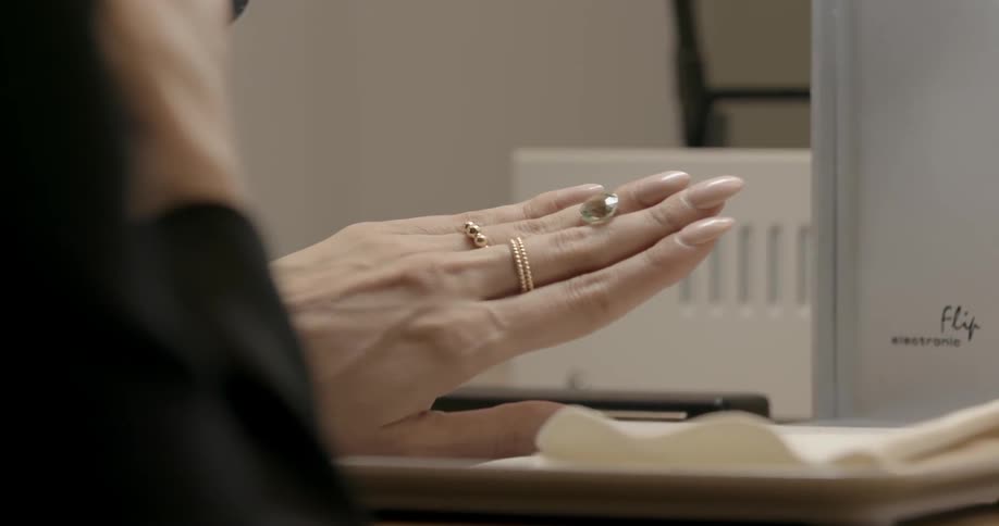 A woman looking at her hand with rings on and in between her fingers