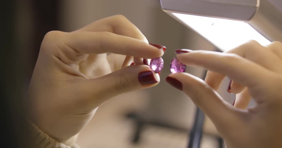 A person is examining two jewels