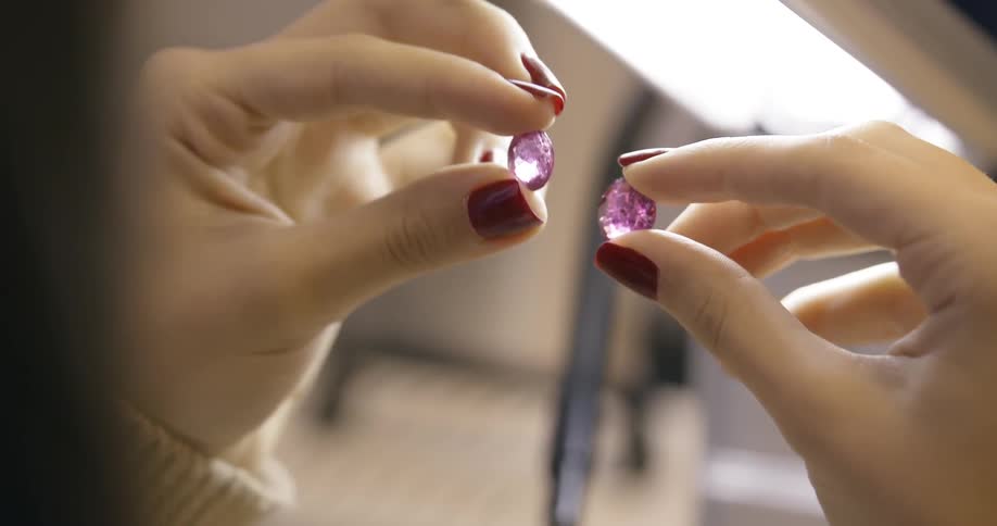 Woman holds purple jewels up to the light
