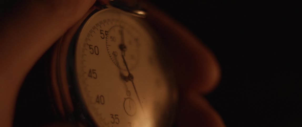 A close up view of someone holding a watch and watching a fire in the glass