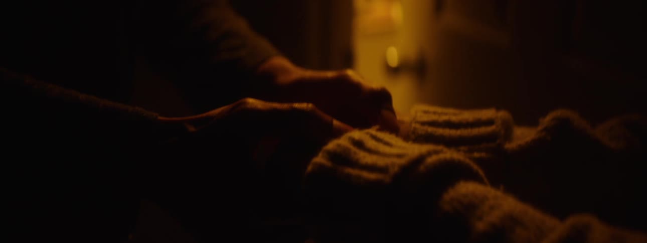 Two people in a dark room holding hands
