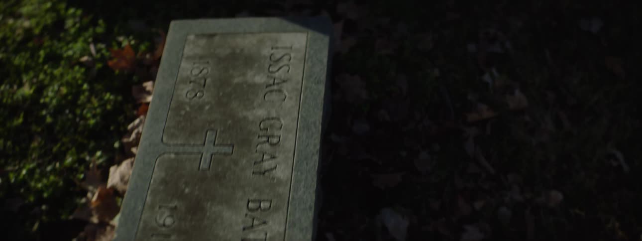 A lowangle panning shot moves across several old gravestones in a cemetery revealing different names and dates the names visible include alice mariah batey issac gray batey myrtle batey and james patrick batey the video showcases t
