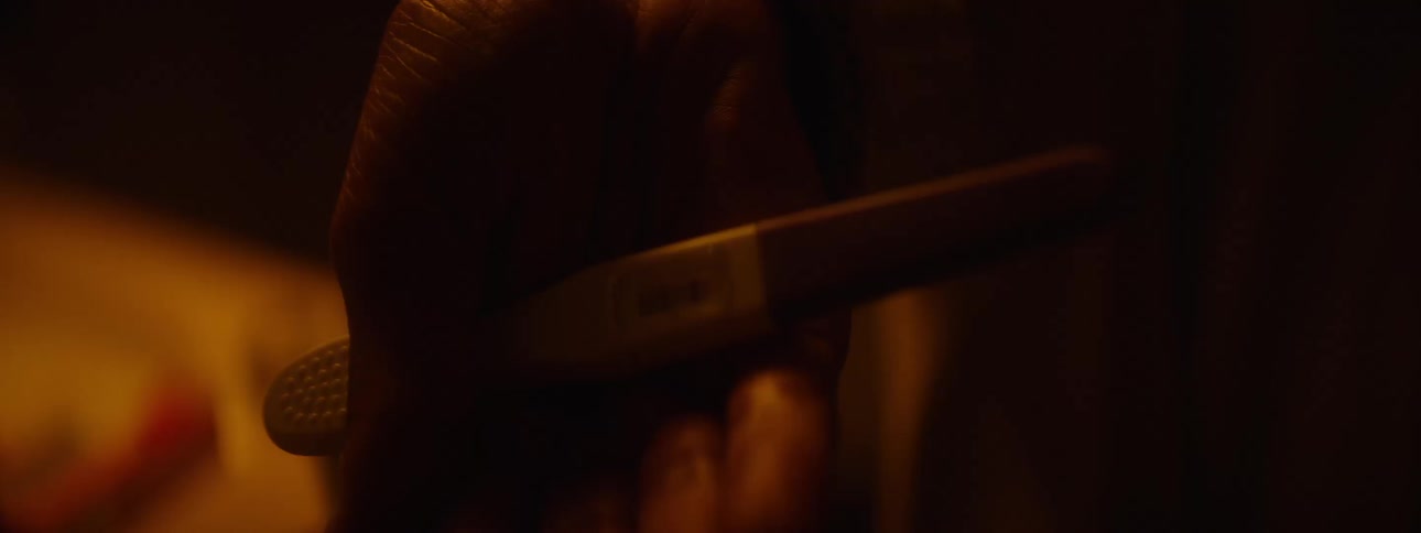 A persons hand holds a pregnancy test as the positive result slowly comes into view