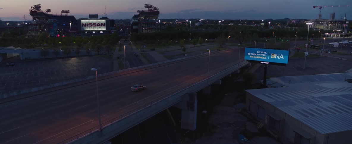 Car driving on an elevated highway with the city lights in the background at dusk