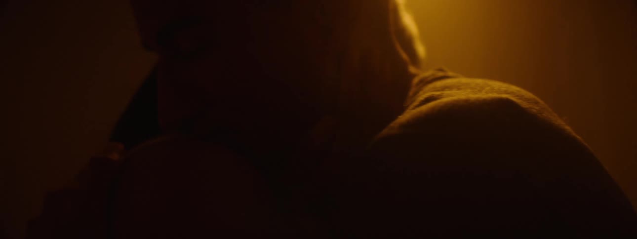 A young couple looking at each other eyes and hugging in a indoor setting with a warm light