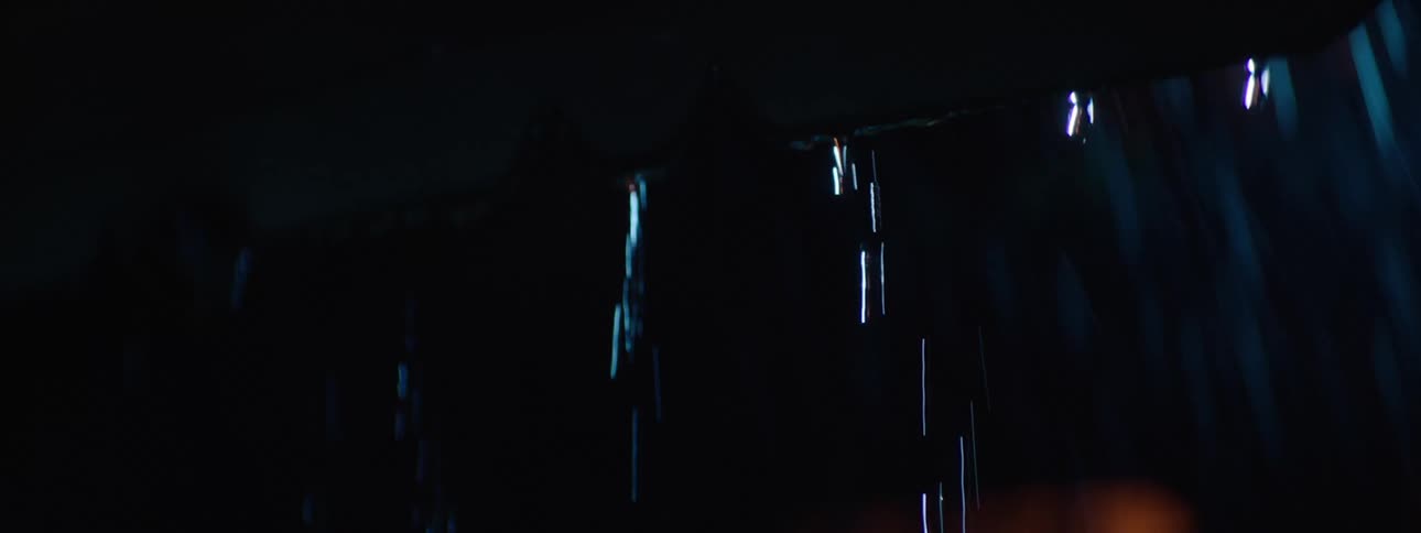 Water running down the roof on a rainy day at night