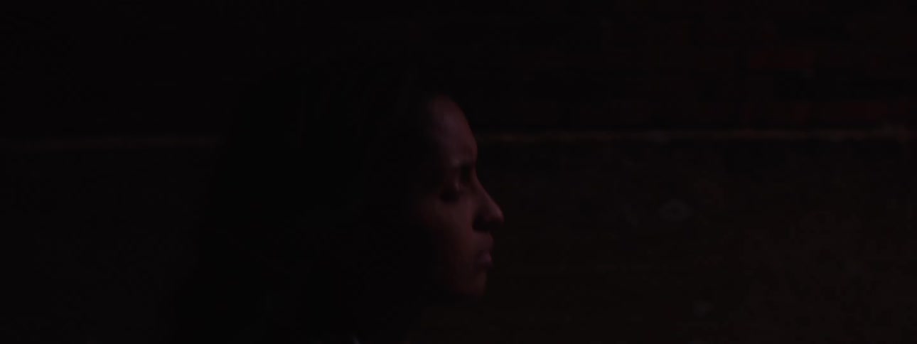 The woman is walking down the alley at night