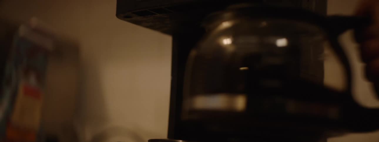 Person taking a teapot from a coffee maker