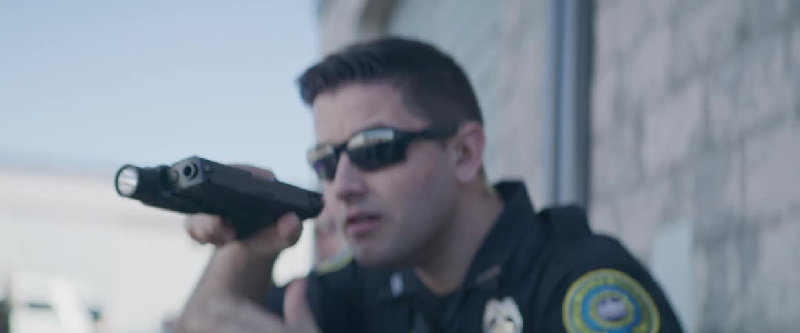 Police officer wearing sunglasses aiming a gun during an operation