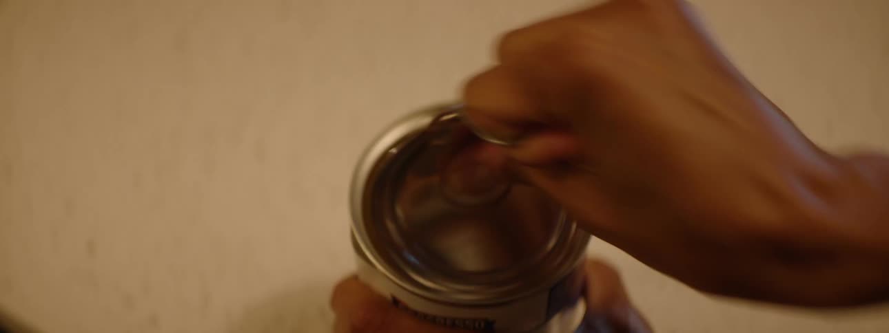 Female opening a food can placed on a countertop in a kitchen