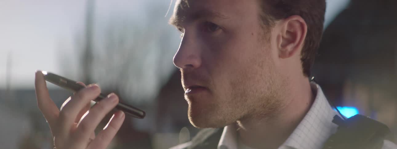 A police negotiator holds up his phone to his mouth to talk