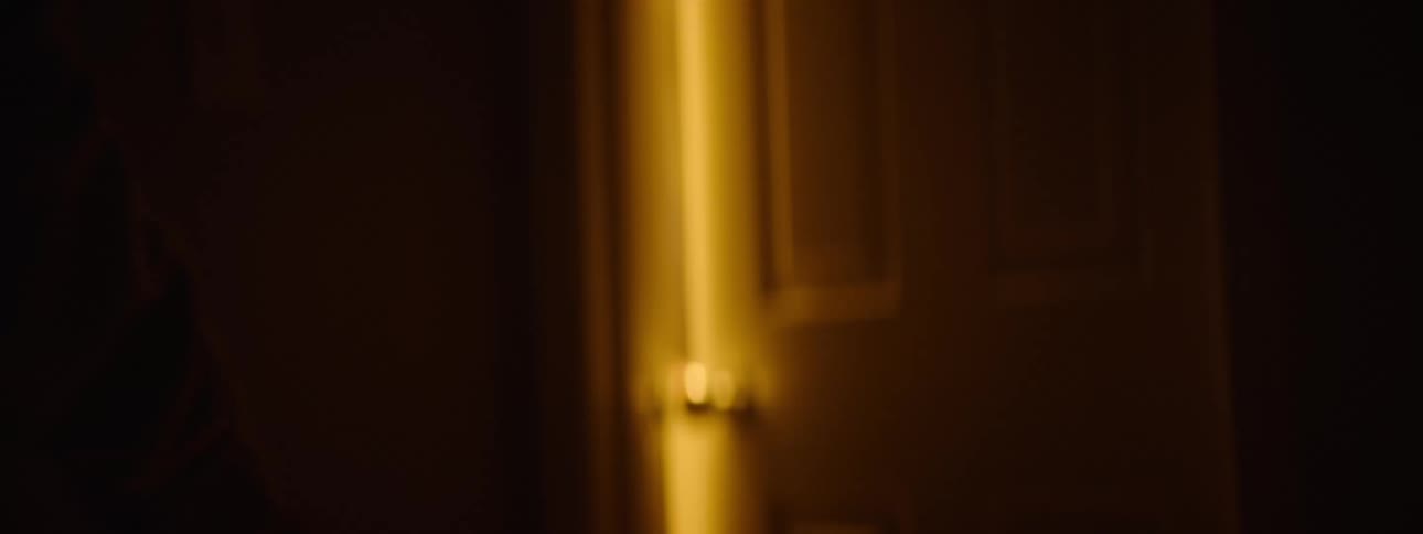 Person walking towards a door with a warm light