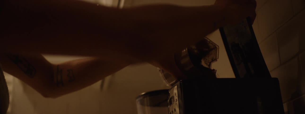 A persons hands transfer freshly ground coffee from a grinder to a coffee maker