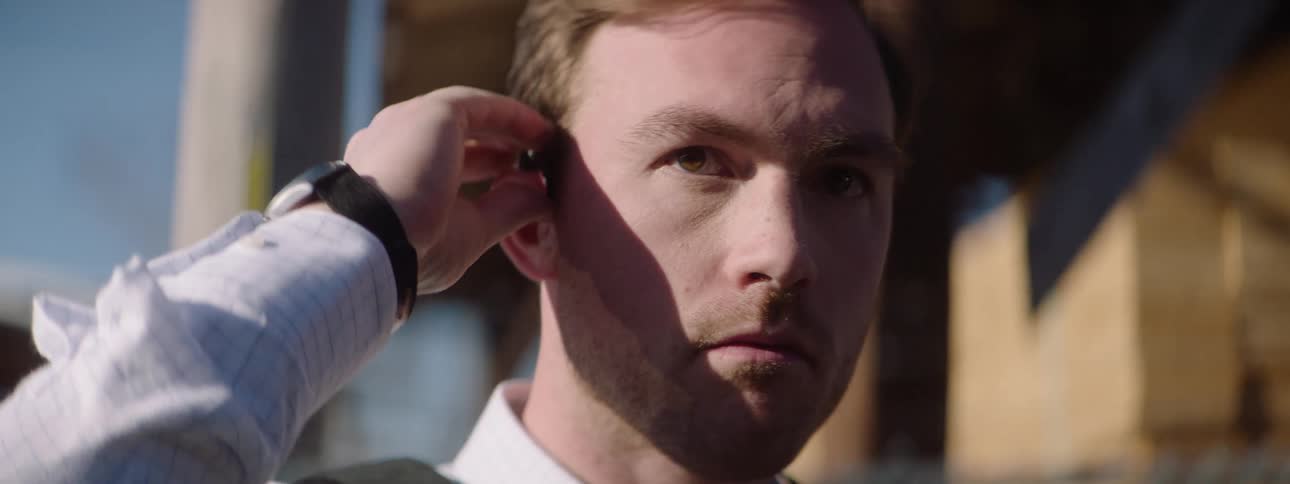 A person putting a device to their ear with a focused facial expression
