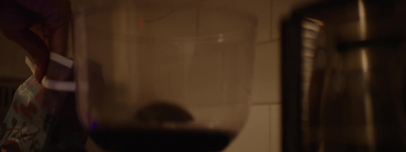 Dark roast coffee beans are poured into the transparent hopper of a coffee grinder